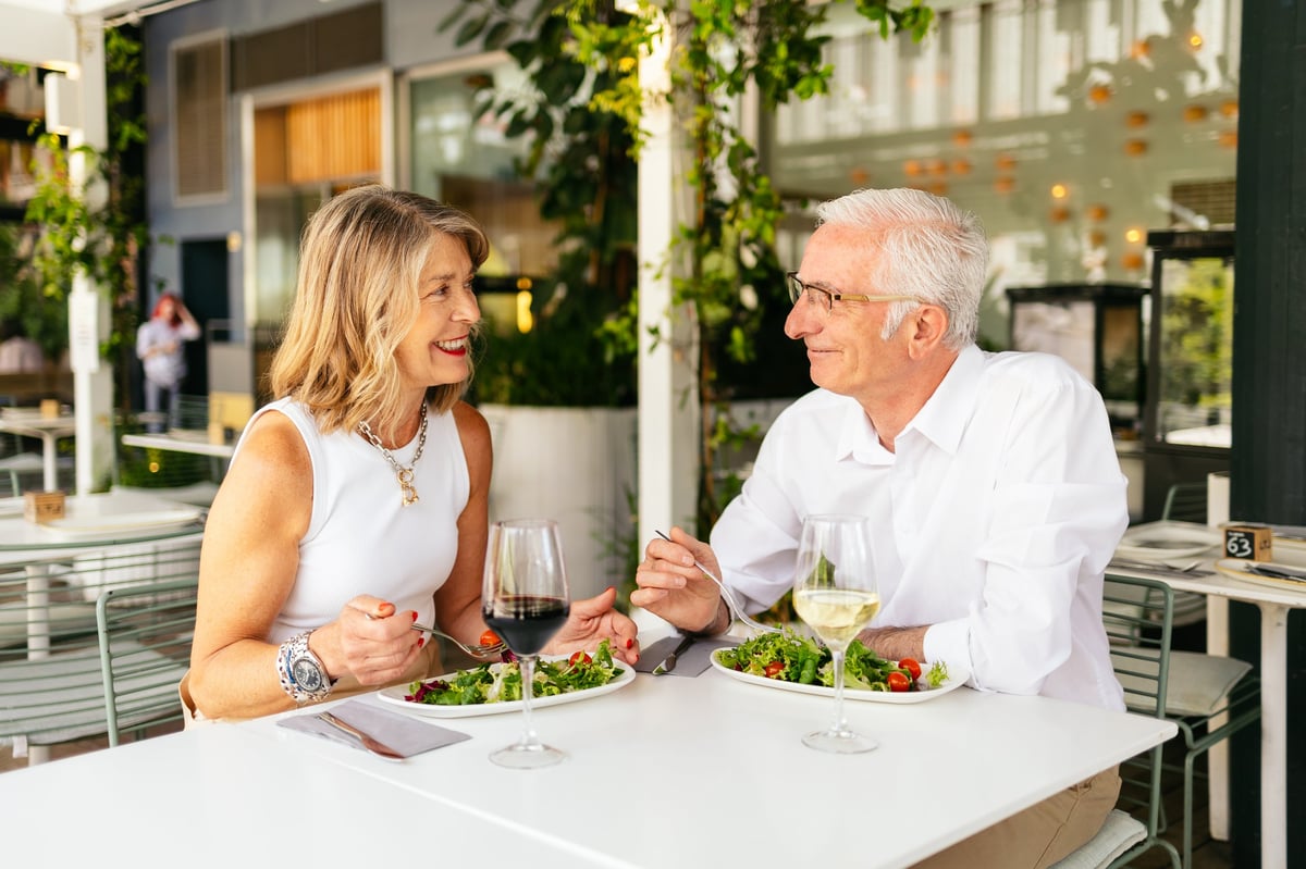 Couple enjoying wine and salad at an outdoor restaurant