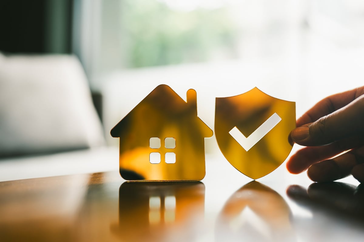 Golden shield with checkmark symbolizing home insurance and property protection