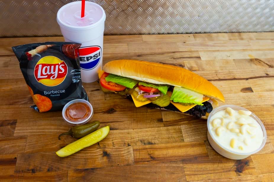 Fast food meal arrangement on wooden table with hot dog, Lays chips, drink, and condiments